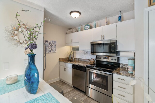 kitchen with light hardwood / wood-style flooring, stainless steel appliances, sink, decorative backsplash, and white cabinets