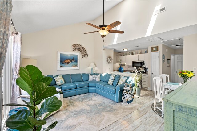 living room with light wood-type flooring, high vaulted ceiling, and ceiling fan