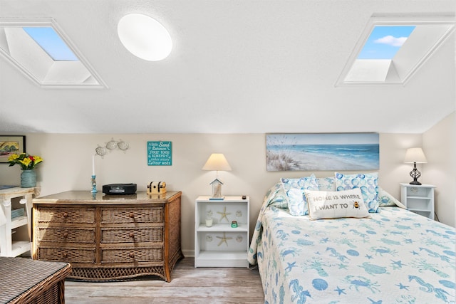 bedroom featuring light hardwood / wood-style flooring and a skylight