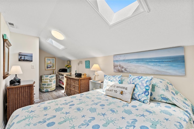 bedroom featuring vaulted ceiling with skylight and hardwood / wood-style floors