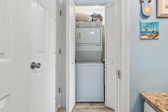 clothes washing area with light hardwood / wood-style flooring and stacked washing maching and dryer