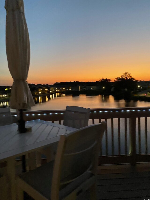 deck at dusk featuring a water view