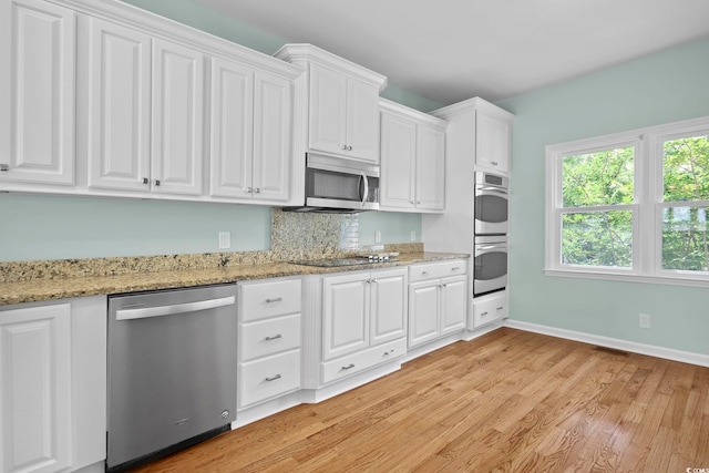 kitchen featuring light hardwood / wood-style flooring, white cabinetry, appliances with stainless steel finishes, and light stone counters