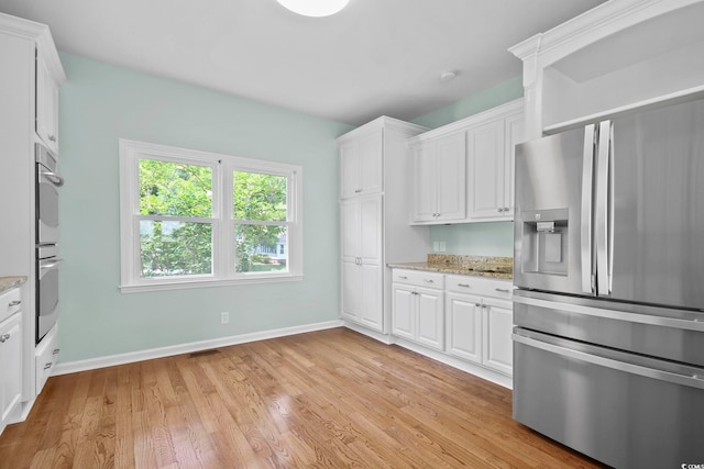 kitchen with light wood-type flooring, white cabinetry, stainless steel appliances, and light stone counters