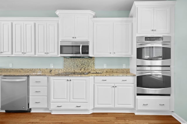 kitchen featuring light stone counters, white cabinets, appliances with stainless steel finishes, and light hardwood / wood-style floors