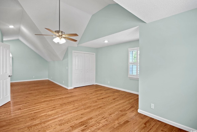 empty room featuring ceiling fan, a textured ceiling, light wood-type flooring, and lofted ceiling