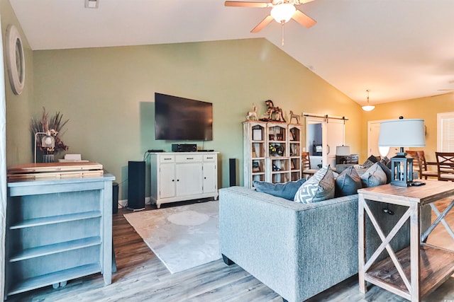 living room with a barn door, lofted ceiling, ceiling fan, and hardwood / wood-style flooring