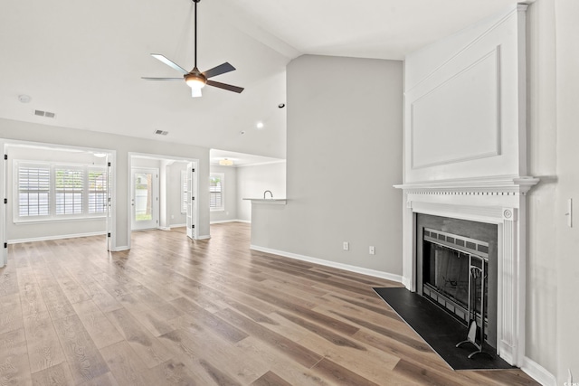 unfurnished living room featuring light hardwood / wood-style flooring, ceiling fan, and high vaulted ceiling