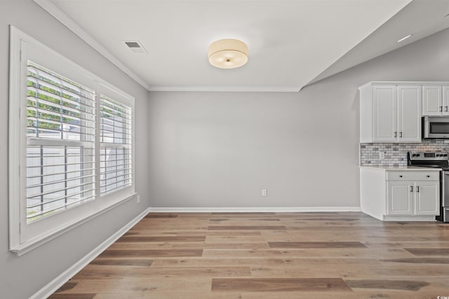 unfurnished dining area with ornamental molding and light hardwood / wood-style floors