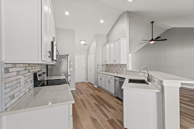 kitchen with light hardwood / wood-style floors, tasteful backsplash, kitchen peninsula, sink, and ceiling fan