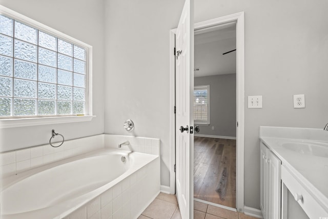 bathroom featuring tile patterned flooring, vanity, and a relaxing tiled tub