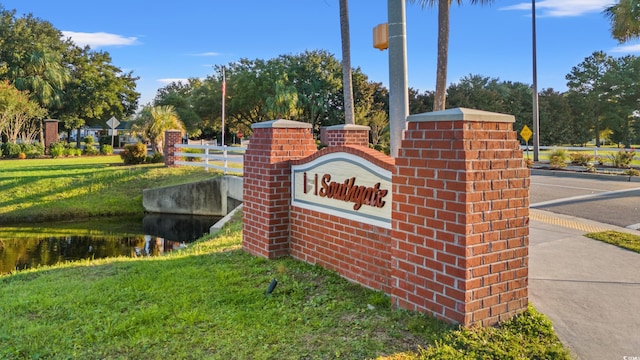 community sign featuring a water view and a lawn