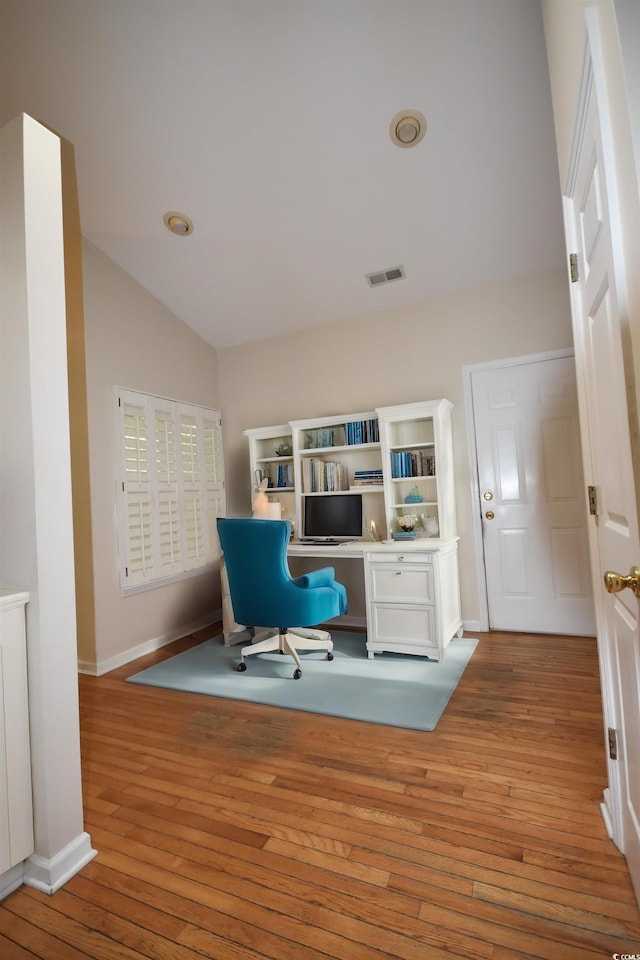 office area featuring light wood-type flooring, baseboards, visible vents, and lofted ceiling