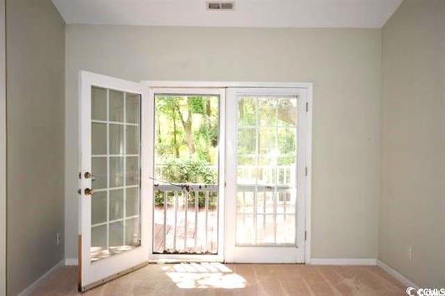 doorway featuring visible vents, light carpet, and baseboards