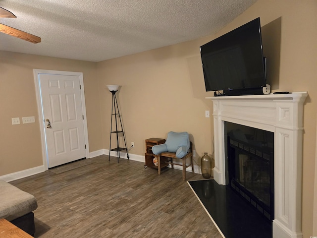 living area featuring dark hardwood / wood-style floors, a textured ceiling, and ceiling fan
