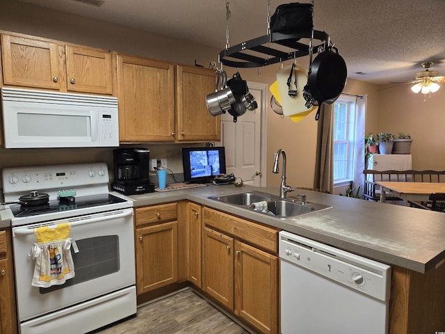 kitchen with sink, white appliances, light hardwood / wood-style floors, kitchen peninsula, and a textured ceiling