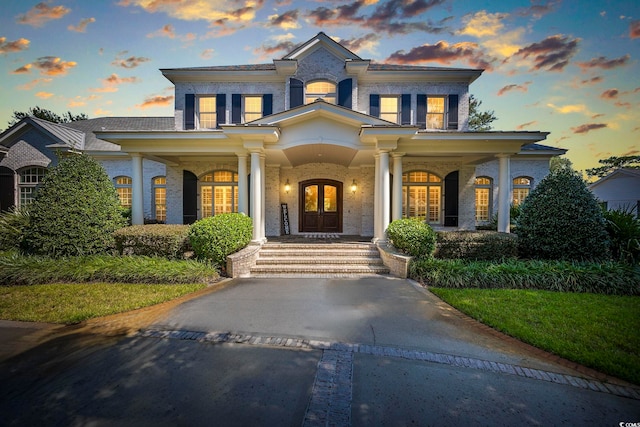 view of front facade with brick siding, a porch, and french doors