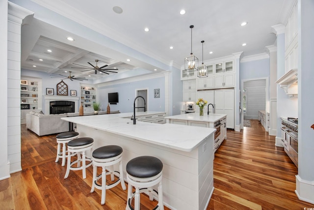 kitchen featuring dark wood-style floors, a spacious island, coffered ceiling, and a fireplace