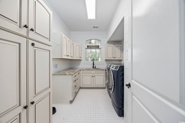 laundry room featuring cabinet space, visible vents, independent washer and dryer, light floors, and a sink