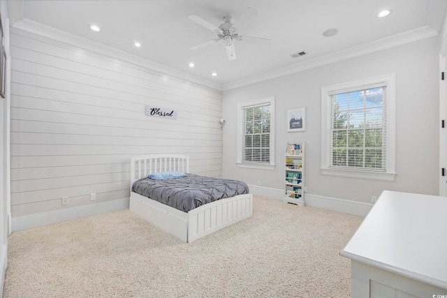 bedroom with wood walls, ceiling fan, crown molding, and carpet floors