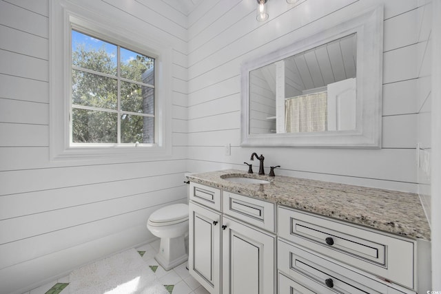 full bath featuring toilet, tile patterned flooring, wooden walls, and vanity