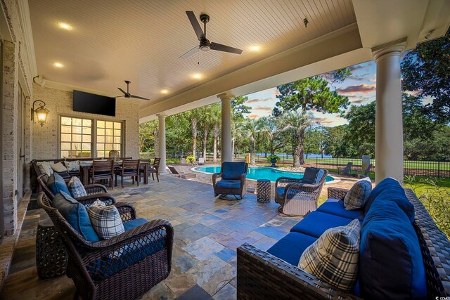 patio terrace at dusk with a fenced in pool, ceiling fan, and outdoor lounge area