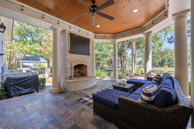 view of patio / terrace with an outdoor brick fireplace, a grill, fence, and ceiling fan