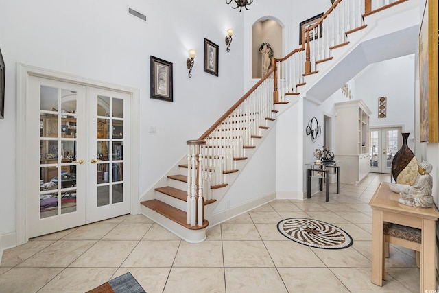 stairs with a high ceiling, tile patterned floors, and french doors