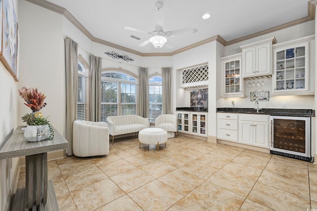 living area featuring crown molding, indoor wet bar, beverage cooler, and ceiling fan