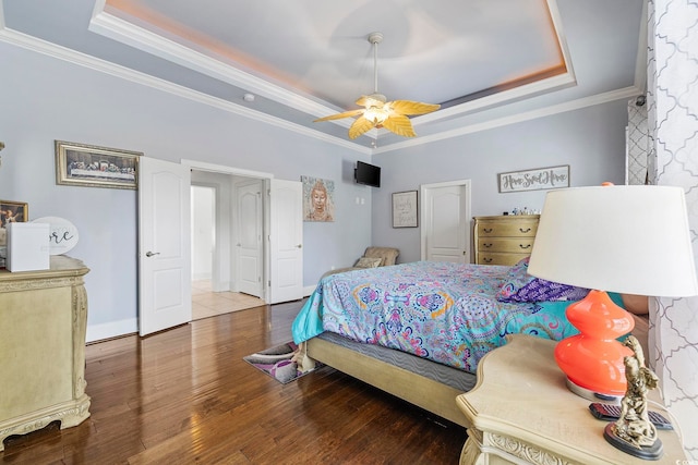 bedroom with a tray ceiling, hardwood / wood-style flooring, crown molding, and ceiling fan