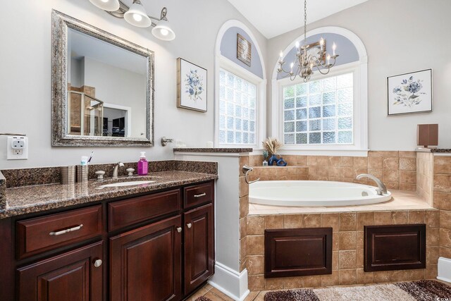 bathroom featuring vanity, tiled tub, a notable chandelier, and tile patterned floors