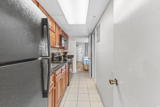 kitchen featuring black appliances, a drop ceiling, and light tile patterned floors