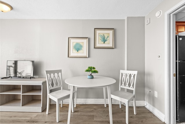 dining space with a textured ceiling and hardwood / wood-style flooring