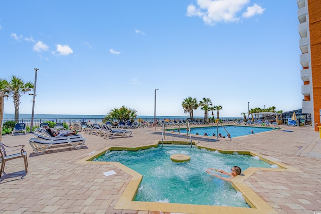 view of pool with a water view and a patio