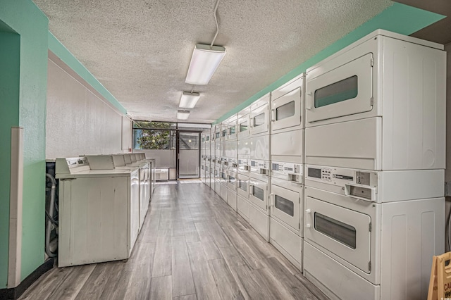 washroom with a textured ceiling, light wood-type flooring, and stacked washer / dryer