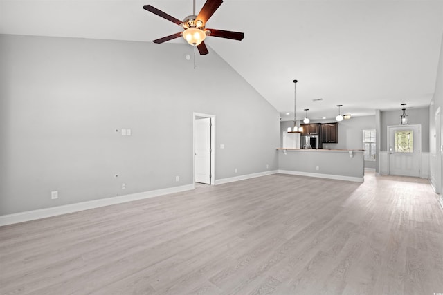 unfurnished living room with a ceiling fan, light wood-type flooring, high vaulted ceiling, and baseboards