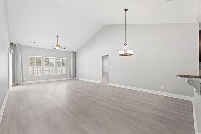 unfurnished living room featuring visible vents, high vaulted ceiling, light wood-type flooring, baseboards, and ceiling fan with notable chandelier