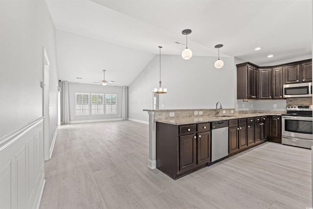 kitchen featuring light wood-type flooring, stainless steel appliances, light stone counters, kitchen peninsula, and ceiling fan