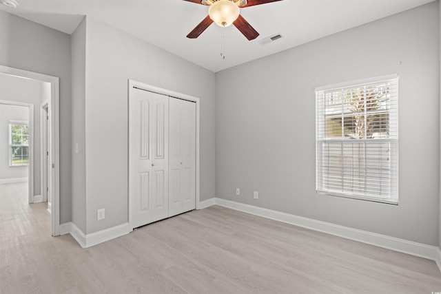 unfurnished bedroom featuring ceiling fan, visible vents, baseboards, a closet, and light wood finished floors