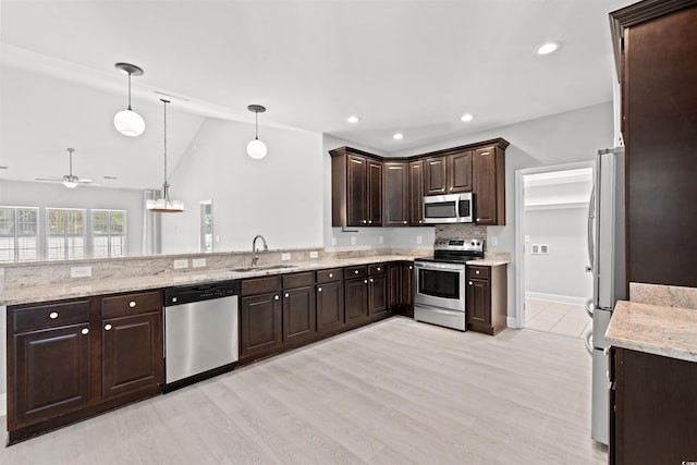 kitchen featuring dark brown cabinetry, stainless steel appliances, a peninsula, a sink, and pendant lighting