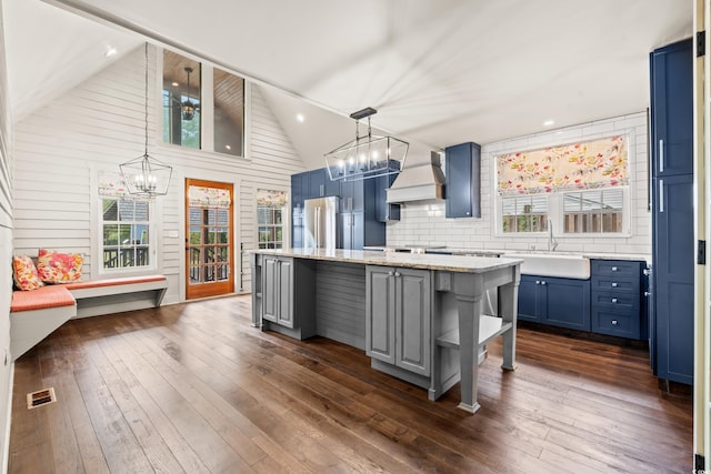 kitchen with stainless steel fridge, a breakfast bar, dark wood-type flooring, sink, and a kitchen island