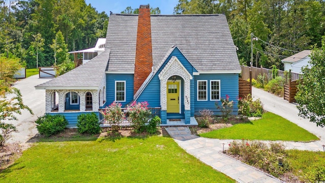 english style home featuring a porch and a front yard