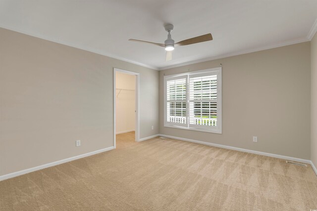 carpeted spare room with crown molding and ceiling fan