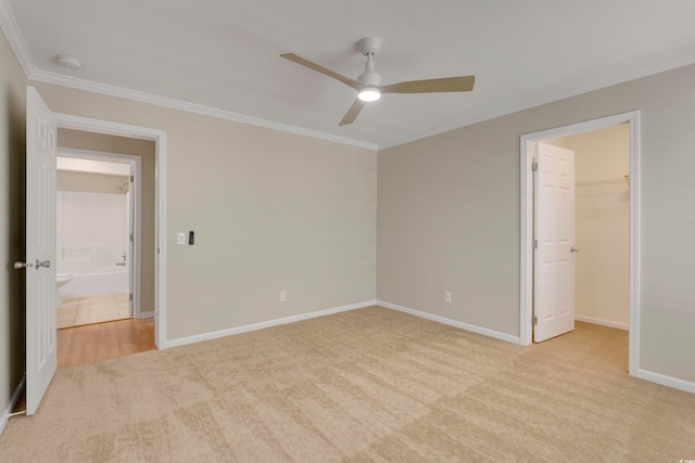 unfurnished bedroom featuring a closet, a spacious closet, light colored carpet, and ceiling fan