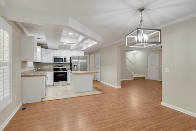 kitchen featuring appliances with stainless steel finishes, light hardwood / wood-style flooring, hanging light fixtures, and a kitchen island