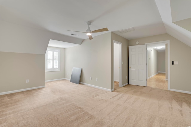 additional living space with ceiling fan, light colored carpet, and vaulted ceiling