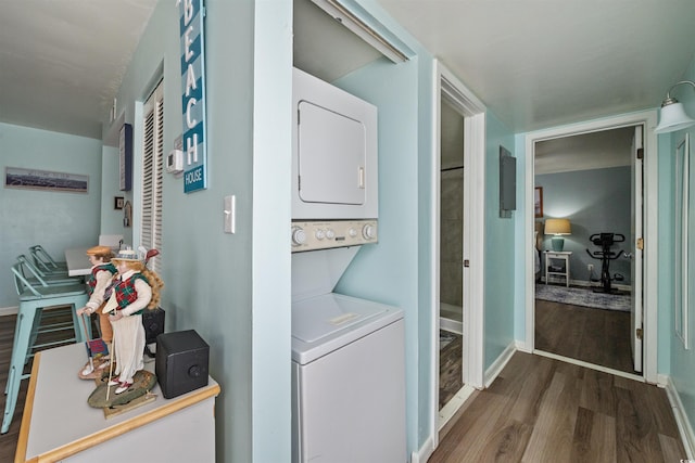 laundry room with stacked washer and clothes dryer and dark wood-type flooring