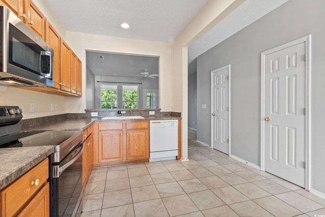 kitchen featuring a textured ceiling, light tile patterned flooring, ceiling fan, and stainless steel appliances