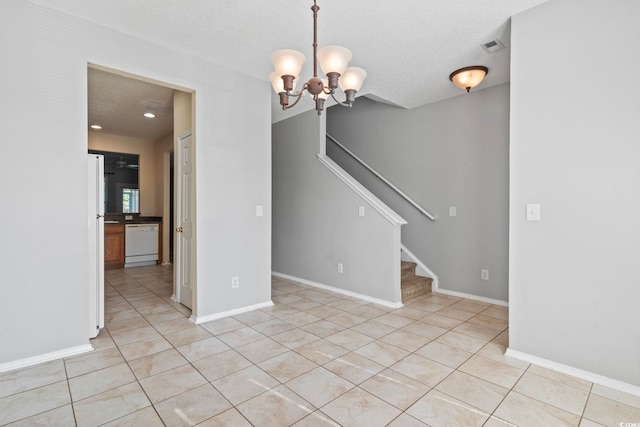 spare room featuring light tile patterned floors, a textured ceiling, and a notable chandelier