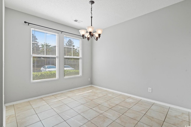 unfurnished room featuring a notable chandelier, light tile patterned floors, and a textured ceiling